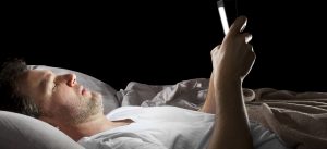 Male in bed browsing the internet late with a tablet